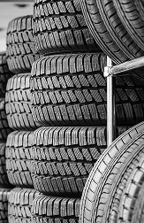 Close-up grayscale view of vertically stacked rubber tires showing deep, rugged tread patterns.