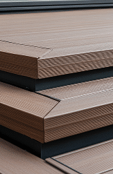 Close-up of brown composite decking steps with grooved wood-grain texture and black risers meeting at a corner.